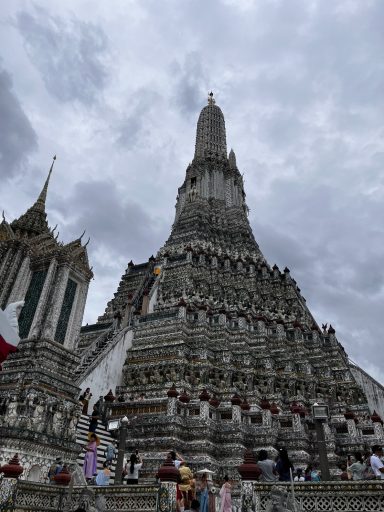 Pagoda con múltiples niveles y figuras religiosas, bajo un cielo nublado.