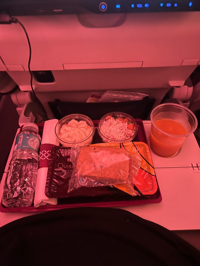 Comida de avión con dos recipientes, un batido y agua embotellada.