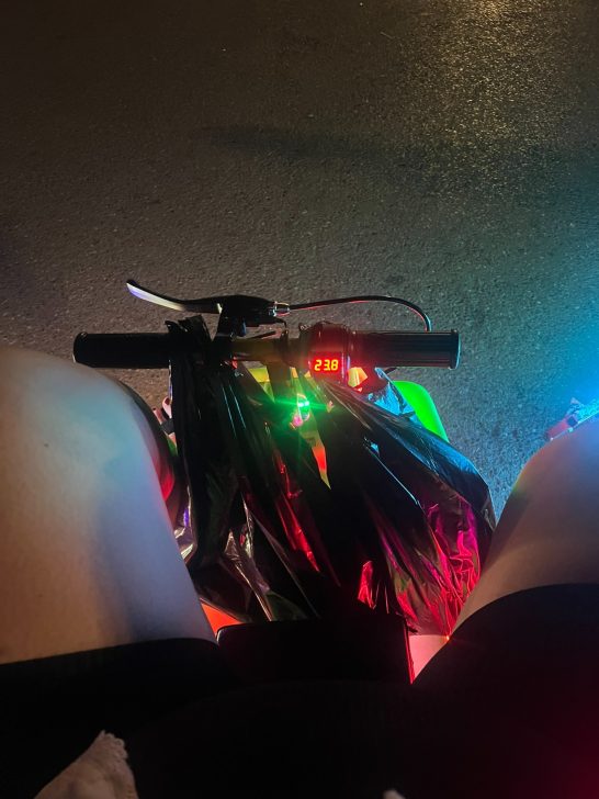 Vista desde arriba de un volante de bicicleta con luces coloridas de noche.