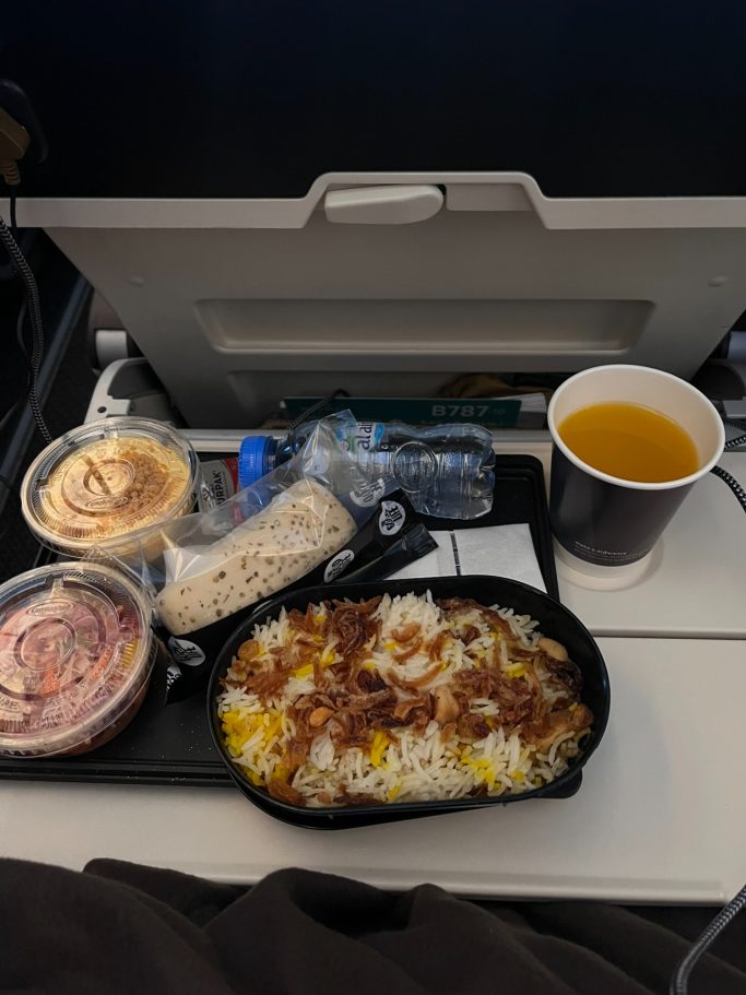 Comida de avión: arroz con carne, ensalada, un postre y una bebida.