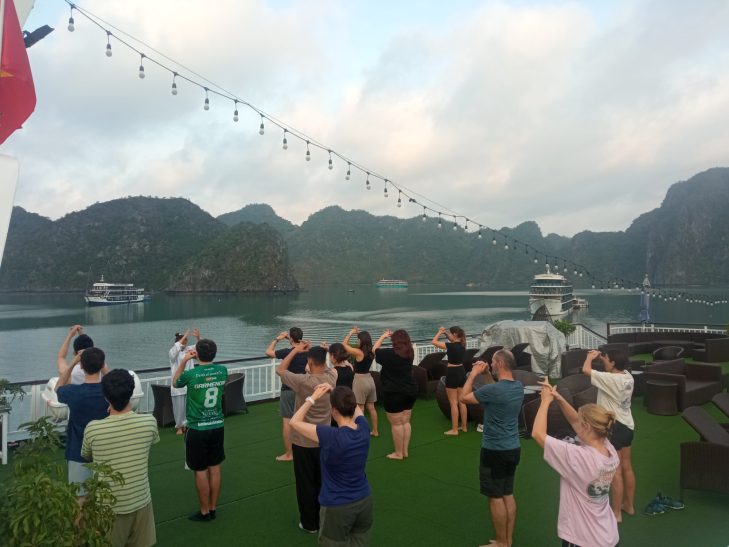 Grupo de personas realizando ejercicios de yoga en una terraza con vistas a montañas.