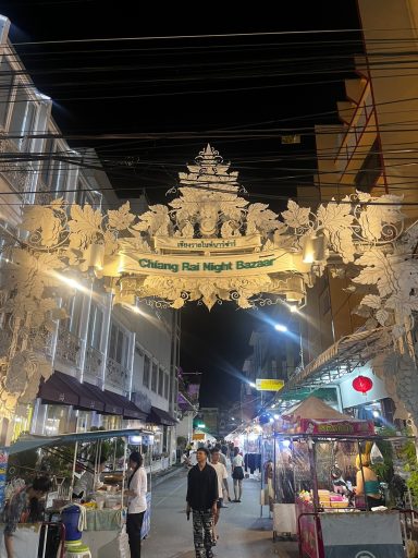 Calle iluminada con decoraciones festivas y puestos de comida.