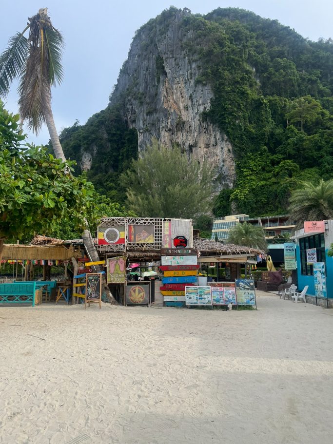 Paisaje costero con cabañas de colores y una montaña al fondo.