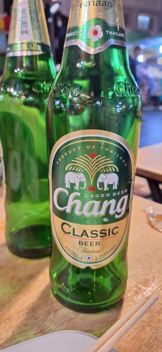 Botella de cerveza Chang Classic, con etiqueta verde y logos de elefantes.