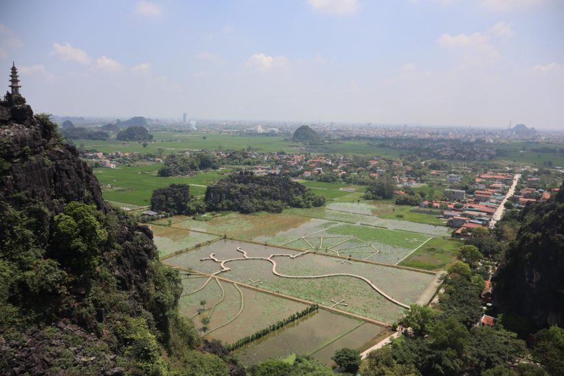 Vista panorámica de campos de arroz y un pueblo rodeado de montañas.