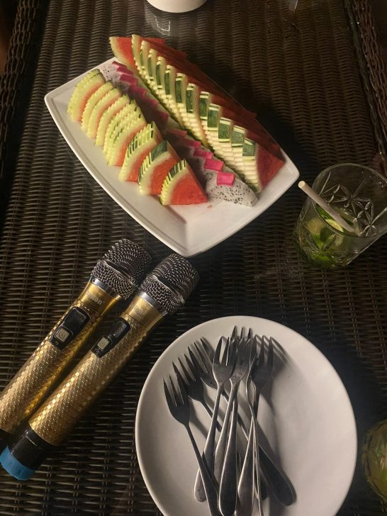 Plato con sandía y melón, micrófonos dorados y un plato con cucharas.