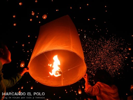 Personas lanzando un globo de luz en la oscuridad de la noche.