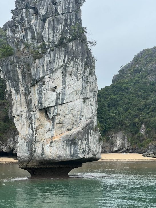 Roca imponente sobre el agua, rodeada de colinas verdes.