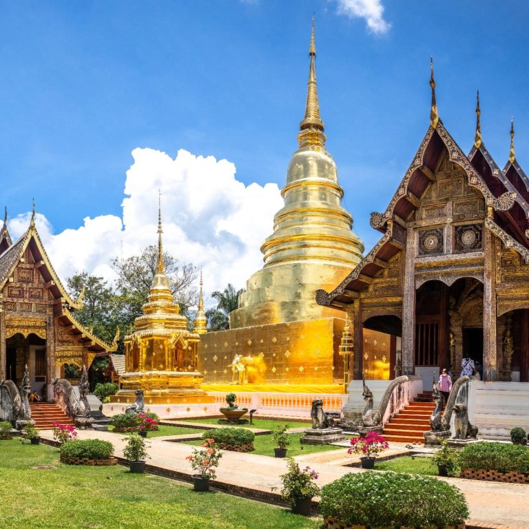 Templo budista con stupas doradas y arquitectura tradicional en un entorno verde.