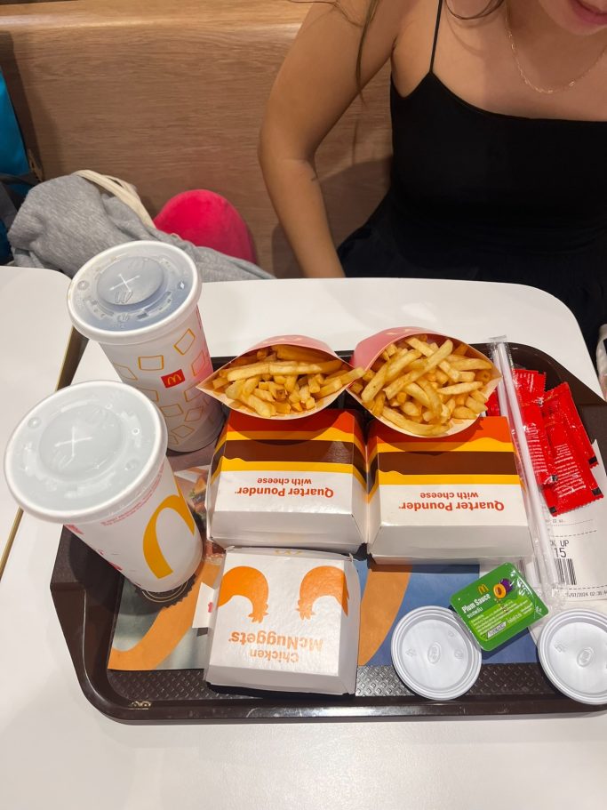 Bandeja con bebidas, hamburguesas, papas fritas y salsas de un restaurante de comida rápida.