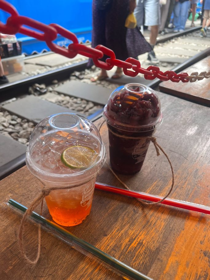Bebidas en vasos transparentes con frutas, cerca de rieles de tren.