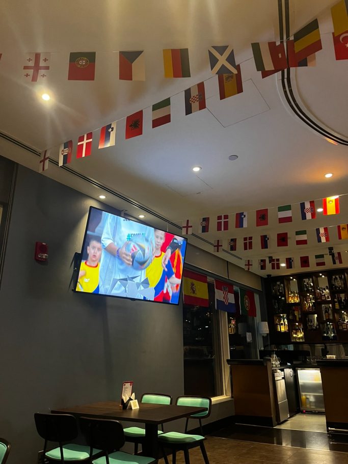 Pantalla con un evento deportivo, decorada con banderas de varios países.