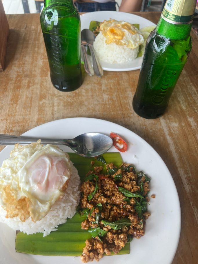 Plato con arroz, pollo salteado y huevo frito, acompañado de dos botellas de cerveza.